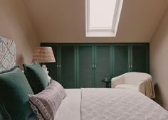 a bedroom with green shutters and a white bed in front of a skylight