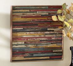 a vase filled with flowers next to a wooden wall art