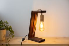 a light that is sitting on top of a wooden shelf next to a potted plant