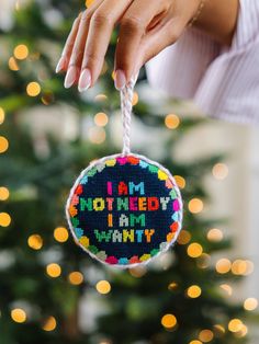 a hand holding a christmas ornament that says i am not needy i am wanty