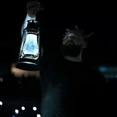 a man holding up a lantern in the dark