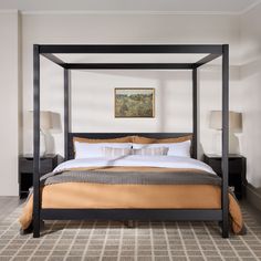 a four poster bed in a bedroom with carpeted flooring and paintings on the wall