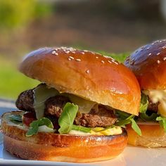 two hamburgers with cheese and lettuce on them are sitting on a plate