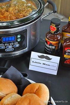 some hot dogs and other condiments sit on a table next to an electric pressure cooker