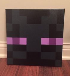 a black box with purple squares on it sitting on a wooden floor next to a wall