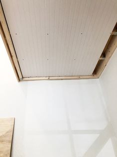 an unfinished room with white walls and wood trimmings on the ceiling is seen from above