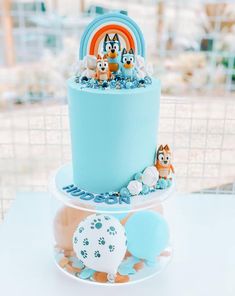 two tiered cake with blue frosting and animals on top