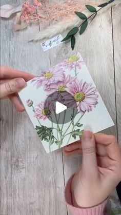 someone holding up a card with flowers on it