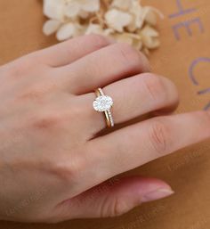 a woman's hand with a diamond ring on top of her finger and flowers in the background