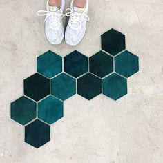 a pair of white tennis shoes sitting on top of a green hexagonal tile floor