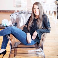 a woman sitting on top of a chair with her legs crossed and smiling at the camera