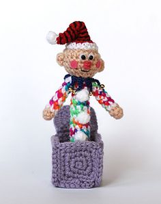 a small crocheted doll with a red and white hat in a purple basket