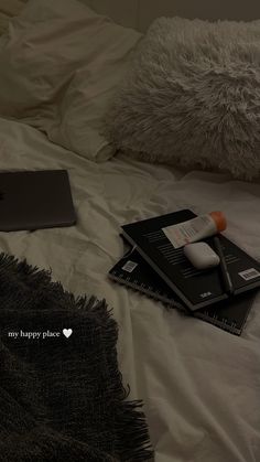 an apple laptop computer sitting on top of a white bed next to two black books