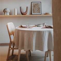 the table is set for two with plates and cups on it in front of shelves