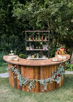 an outdoor bar is decorated with greenery, candles and bottles on it's stand