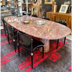 a marble dining table with black chairs and red rug on the floor in front of it