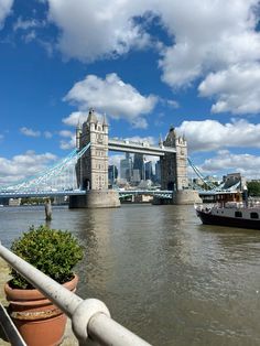 there is a boat going down the river by tower bridge in london, england on a sunny day