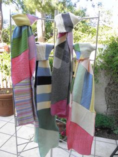 several colorful towels are hanging on a rack in front of a potted plant and tree