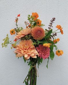 a vase filled with lots of different colored flowers on top of a white table next to a wall