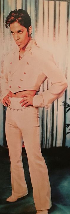 a man standing in front of a curtain with his hands on his hips and wearing white pants