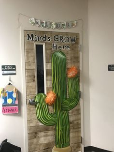 a large cactus plant sitting in front of a door with the words minds grow here on it