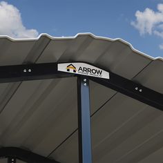 an arrow sign on the side of a metal structure against a blue sky with clouds