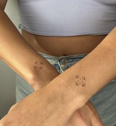 two women's arms with small stars tattooed on the arm and behind their backs