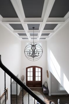 a chandelier hanging from the ceiling in a room with white walls and wood floors