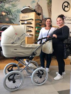 two women standing next to a baby carriage