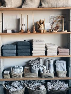 towels and linens are displayed on shelves in the store, with baskets full of them