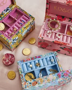 an open jewelry box sitting on top of a table next to other small boxes and coins