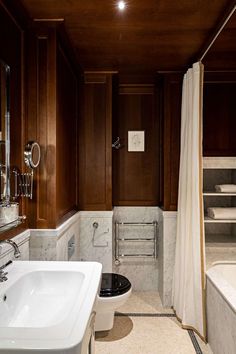 a bathroom with a toilet, sink and bathtub in the middle of wood paneled walls