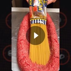 a person holding a bag of pasta in front of a fake meaty dog toy