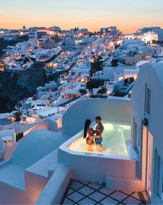 two people are sitting in an outdoor hot tub overlooking the city at sunset or dawn