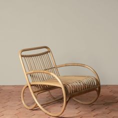 a wooden rocking chair sitting on top of a brick floor next to a white wall