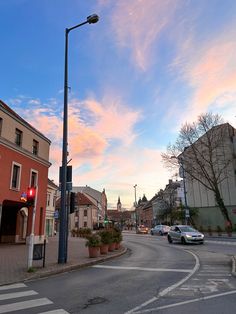 an empty street with cars parked on the side and buildings in the background at sunset