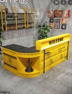 a yellow welcome sign sitting on top of a counter next to a potted plant