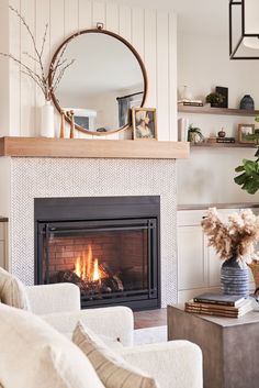 a living room with a fire place in the middle and a mirror above it on the wall