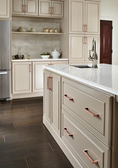 a kitchen with white cabinets and wood floors