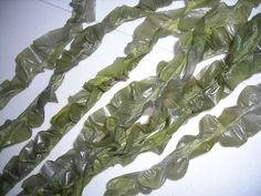 several pieces of green seaweed on a white surface