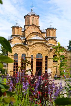 the building has many windows and is surrounded by flowers