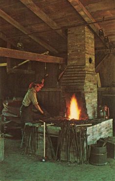 a man standing over a fire in an old fashioned stove with wood and brick on it