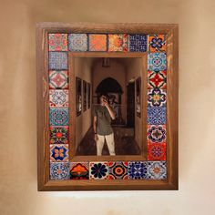 a man taking a selfie in front of a mirror with colorful tiles on it