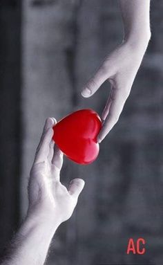 a person holding a red heart in their hand with the other hand reaching for it