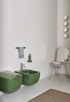 two green sinks in a white bathroom next to a chair