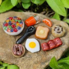 an assortment of miniature food items sitting on top of a rock in front of some plants