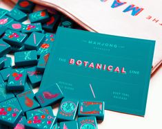 a blue box with pink and red designs on it next to a bag that says mahjung the botanical line