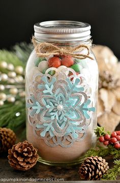 a mason jar filled with snowflakes and pine cones