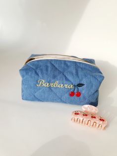 a small blue bag sitting next to a pink toothbrush and hair clip on a white surface