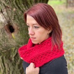 a woman with red hair wearing a red knitted cowgirl neck scarf in front of a tree